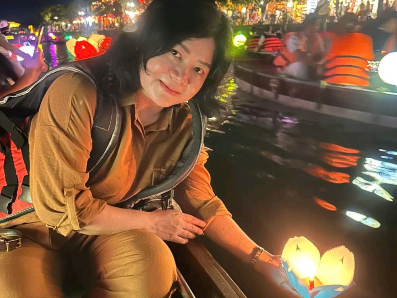 Woman releasing a candle lantern during a lantern boat ride on the river in Hoi An at night